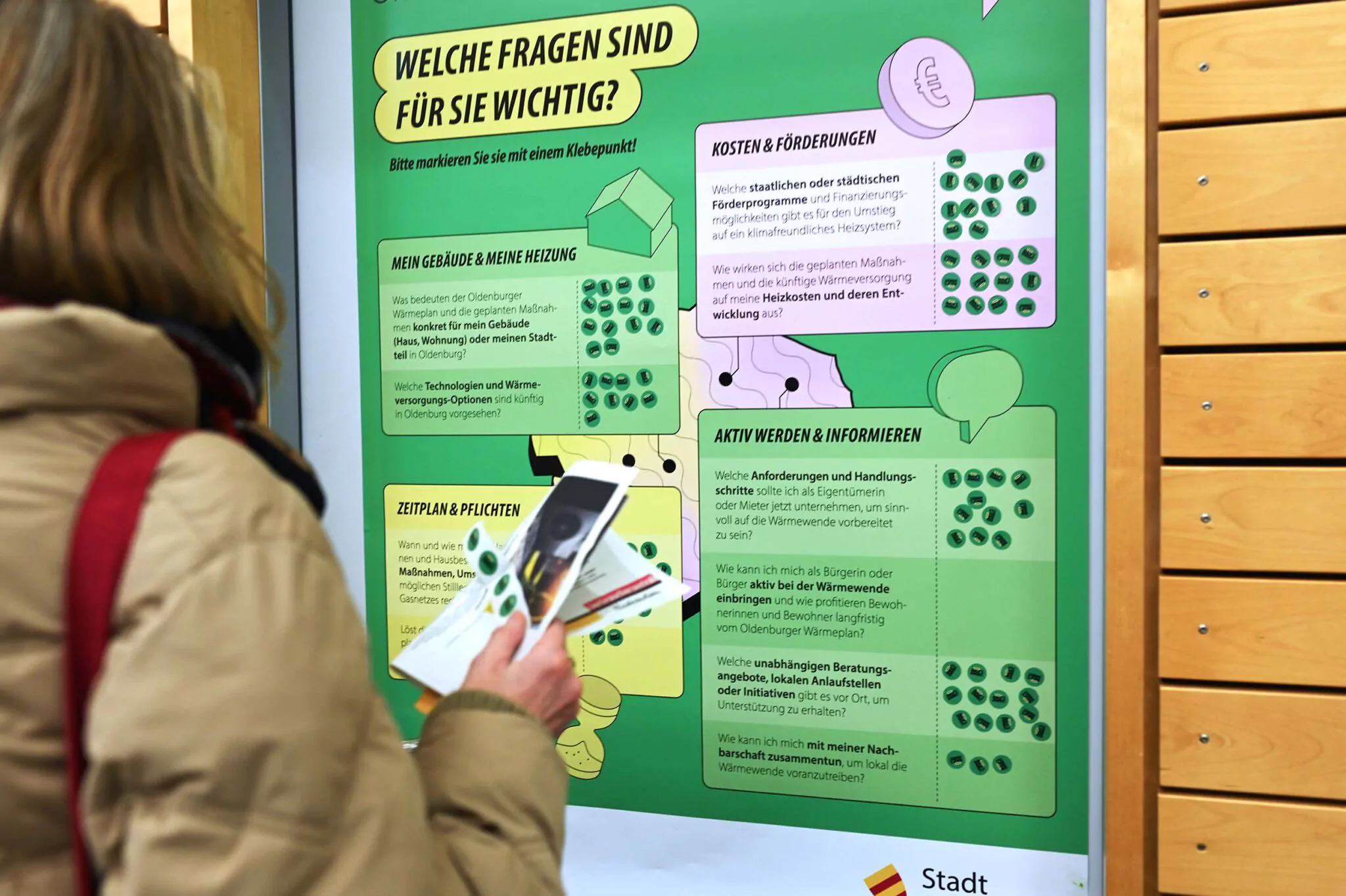 Lebendige Fragen-Wand: Bürgerin priorisiert mit Klebepunkten ihre wichtigsten Fragen zur Wärmeplanung